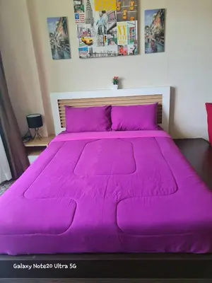 a large bed with a purple bedspread on it at The Naithorn Condo Unit 401 in Nai Thon Beach