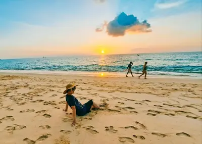 a person sitting on the beach watching the sunset at The Naithorn Condo Unit 401 in Nai Thon Beach