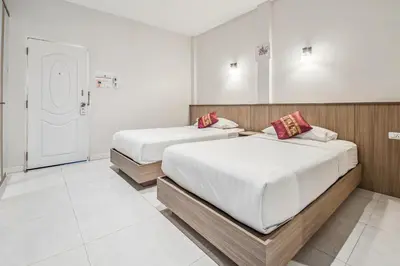 two beds in a room with white walls at Winrisa Place in Nai Yang Beach