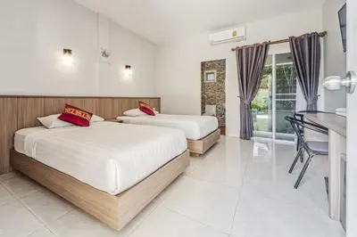 two beds in a room with a table and a desk at Winrisa Place in Nai Yang Beach