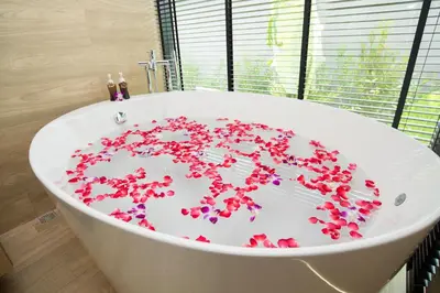 a bath tub filled with red flowers in a bathroom at Pumeria Resort Phuket - SHA Plus in Bang Tao Beach