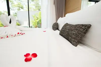 a bedroom with a white bed with red flowers on it at Pumeria Resort Phuket - SHA Plus in Bang Tao Beach