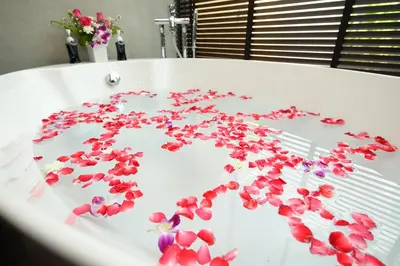 a white bath tub with red flowers on it at Pumeria Resort Phuket - SHA Plus in Bang Tao Beach