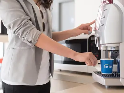 a woman is using a coffee machine at HOP INN Phuket in Phuket Town