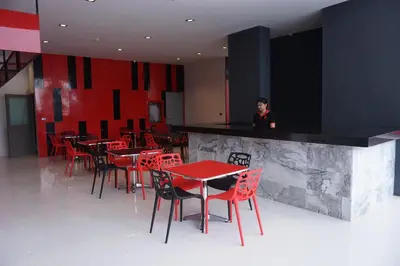 a person standing at a bar with red tables and chairs at Neon Patong in Patong Beach