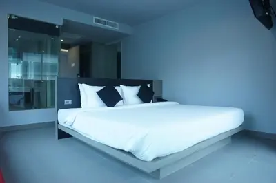 a bedroom with a large white bed with black pillows at Neon Patong in Patong Beach