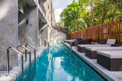 a pool with tables and chairs next to a building at Maneetel Krabi Beachfront-SHA Plus in Ao Nang Beach