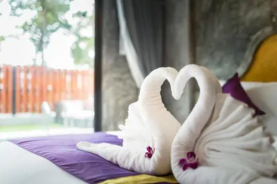 two towels shaped like swans sitting on a bed at Maneetel Krabi Beachfront-SHA Plus in Ao Nang Beach
