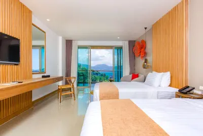 a hotel room with two beds and a television at Wyndham Grand Phuket Kalim Bay in Patong Beach