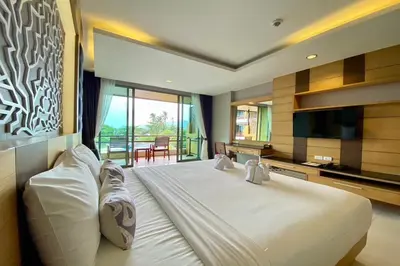 a bedroom with a large white bed and a balcony at Aqua Resort Phuket - Near Beach and Chalong Pier in Rawai Beach