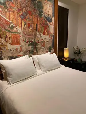 a bedroom with a white bed with a painting on the wall at Tukonnee Villas Koh Yao Noi in Ko Yao Noi