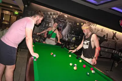a group of men standing around a pool table at Balcony Party Hostel - 18-40 in Ao Nang Beach