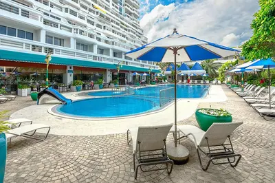 a swimming pool with chairs and an umbrella at Andaman Sea View Apartment - Patong Beach in Patong Beach