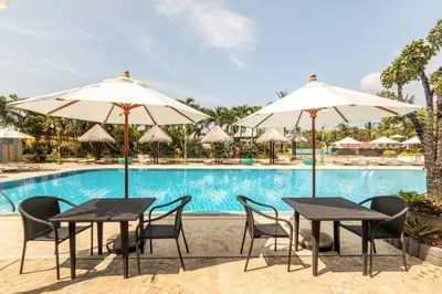 two tables and chairs with umbrellas in front of a pool at Andaman Sea View Apartment - Patong Beach in Patong Beach
