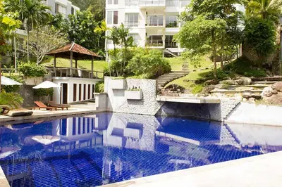 a swimming pool with two chairs and a building at Kamala Hills Serviced Apartments in Kamala Beach