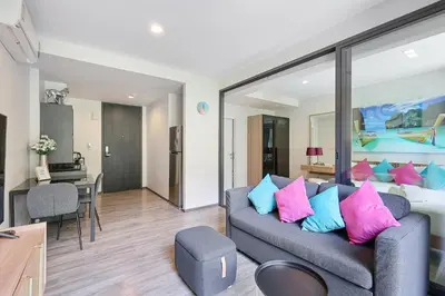 a living room with a couch with pink and blue pillows at The Deck Condominium Patong Beach in Patong Beach