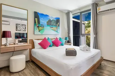 a bedroom with a large bed with pink and blue pillows at The Deck Condominium Patong Beach in Patong Beach