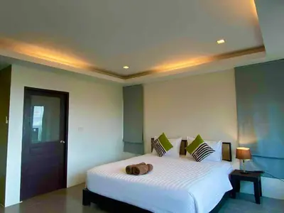 a bedroom with a white bed with a brown bag on it at Sunset Bay View Phuket in Patong Beach