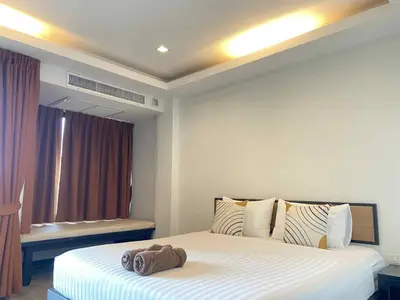 a bedroom with a large white bed and a window at Sunset Bay View Phuket in Patong Beach