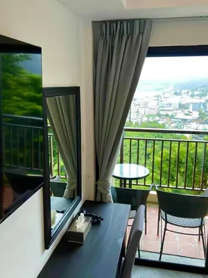 a room with a table and chairs and a balcony at Sunset Bay View Phuket in Patong Beach