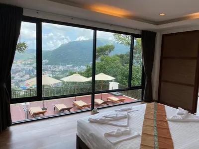a bedroom with a large window with a view at Sunset Bay View Phuket in Patong Beach
