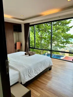 a bedroom with a large bed and a large window at Sunset Bay View Phuket in Patong Beach