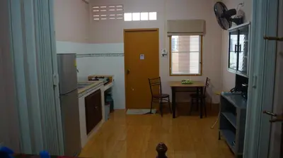 a kitchen with a counter and a table and a door at Kata Apartment in Kata Beach
