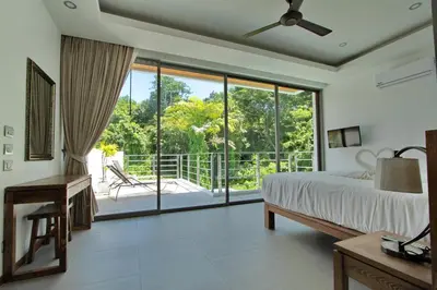 a bedroom with a bed and a sliding glass door at Ya Nui Beach Villas in Rawai Beach