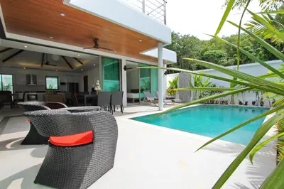 a patio with chairs and a swimming pool at Ya Nui Beach Villas in Rawai Beach