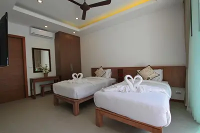a hotel room with two beds with white sheets at Ya Nui Beach Villas in Rawai Beach