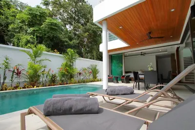 an outdoor patio with chairs and a swimming pool at Ya Nui Beach Villas in Rawai Beach