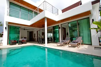 a villa with a swimming pool and a house at Ya Nui Beach Villas in Rawai Beach