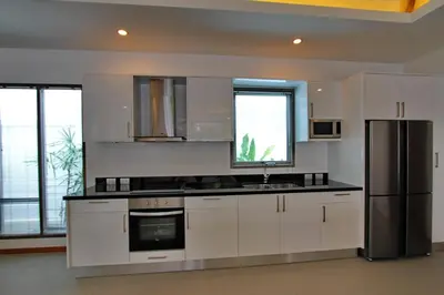 a kitchen with white cabinets and a stainless steel refrigerator at Ya Nui Beach Villas in Rawai Beach