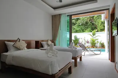 two beds in a room with a view of a patio at Ya Nui Beach Villas in Rawai Beach