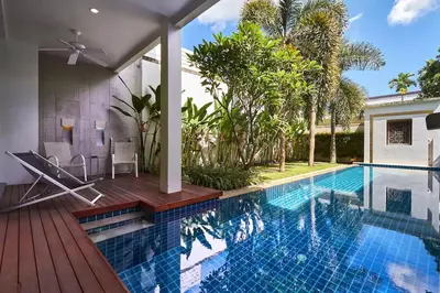 a swimming pool with a wooden deck and a house at Villa Oxygen - Bangtao Beach in Bang Tao Beach