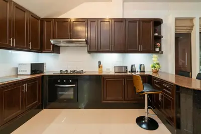 a kitchen with wooden cabinets and a chair in it at Boutique Resort Private Pool Villa - SHA Extra Plus in Thalang