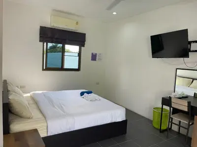 a bedroom with a bed and a television in it at Lotus Bleu Resort & Restaurant in Rawai Beach