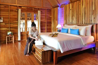 a person sitting on a large bed in a room at Phi Phi Phu Chalet Resort in Phi Phi Don