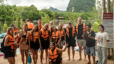 a group of people in orange life jackets standing on a dock at K-Bunk AoNang Center in Ao Nang Beach