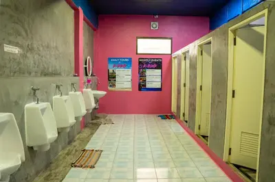 a bathroom with a row of urinals and a pink wall at K-Bunk AoNang Center in Ao Nang Beach
