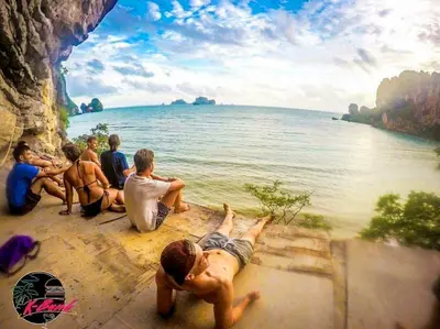 a group of people sitting on a ledge near the water at K-Bunk AoNang Center in Ao Nang Beach