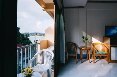 a balcony with chairs and a table and a television at Kata Sun Beach Hotel in Kata Beach