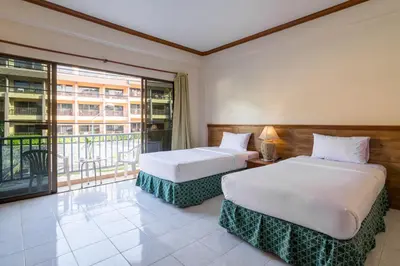 two beds in a room with a balcony at Kata Sun Beach Hotel in Kata Beach