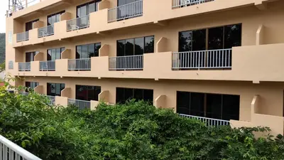 an apartment building with balconies and trees at Kata Sun Beach Hotel in Kata Beach