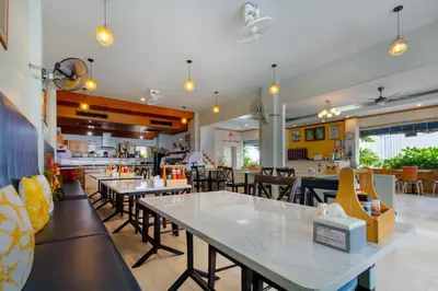 a dining room with tables and chairs in a restaurant at Kata Sun Beach Hotel in Kata Beach