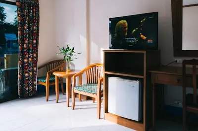 a living room with a tv and a table with chairs at Kata Sun Beach Hotel in Kata Beach