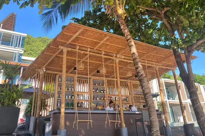 a building with a bar with people sitting at it at My Beach Resort Phuket, Panwa Beach in Panwa Beach