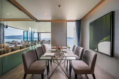 a dining room with a long glass table and chairs at My Beach Resort Phuket, Panwa Beach in Panwa Beach