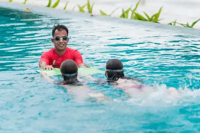 a man in the water with three people on a surfboard at My Beach Resort Phuket, Panwa Beach in Panwa Beach