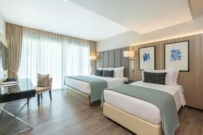 a hotel room with two beds and a chair at My Beach Resort Phuket, Panwa Beach in Panwa Beach